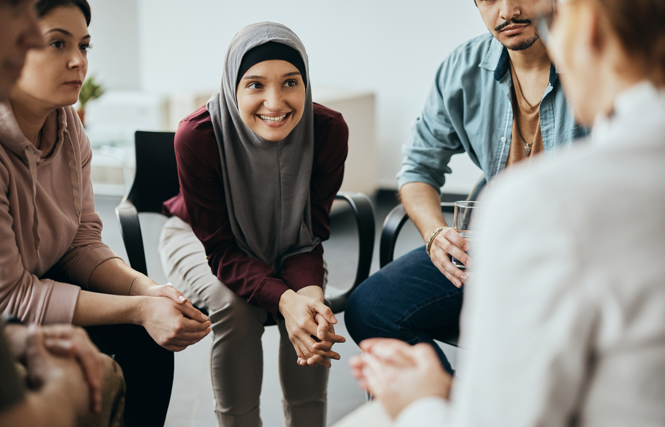 a group of diverse people having group meeting with their therapist at mental health center.