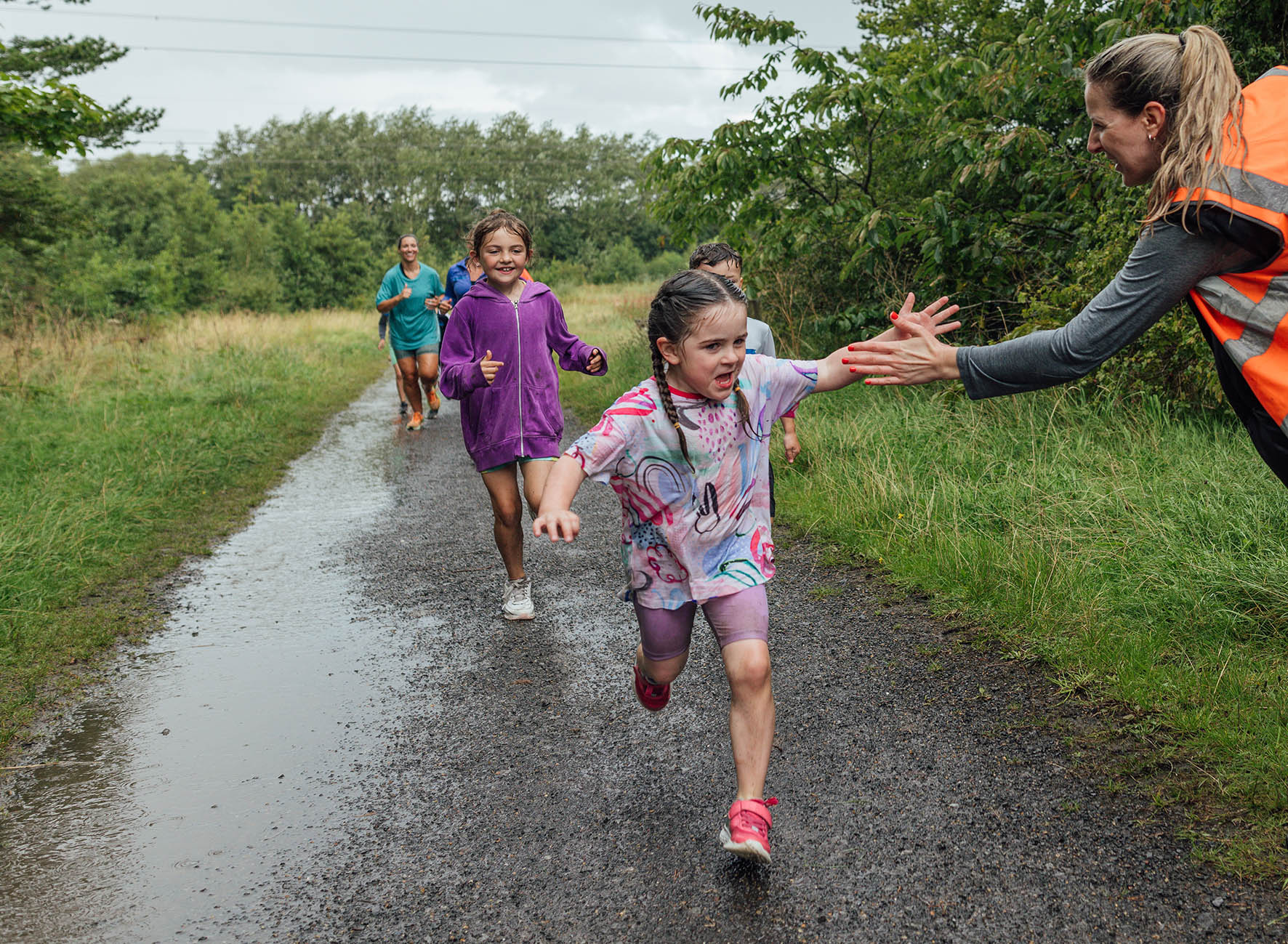 children running and a lane giving a woman in high vis a high five