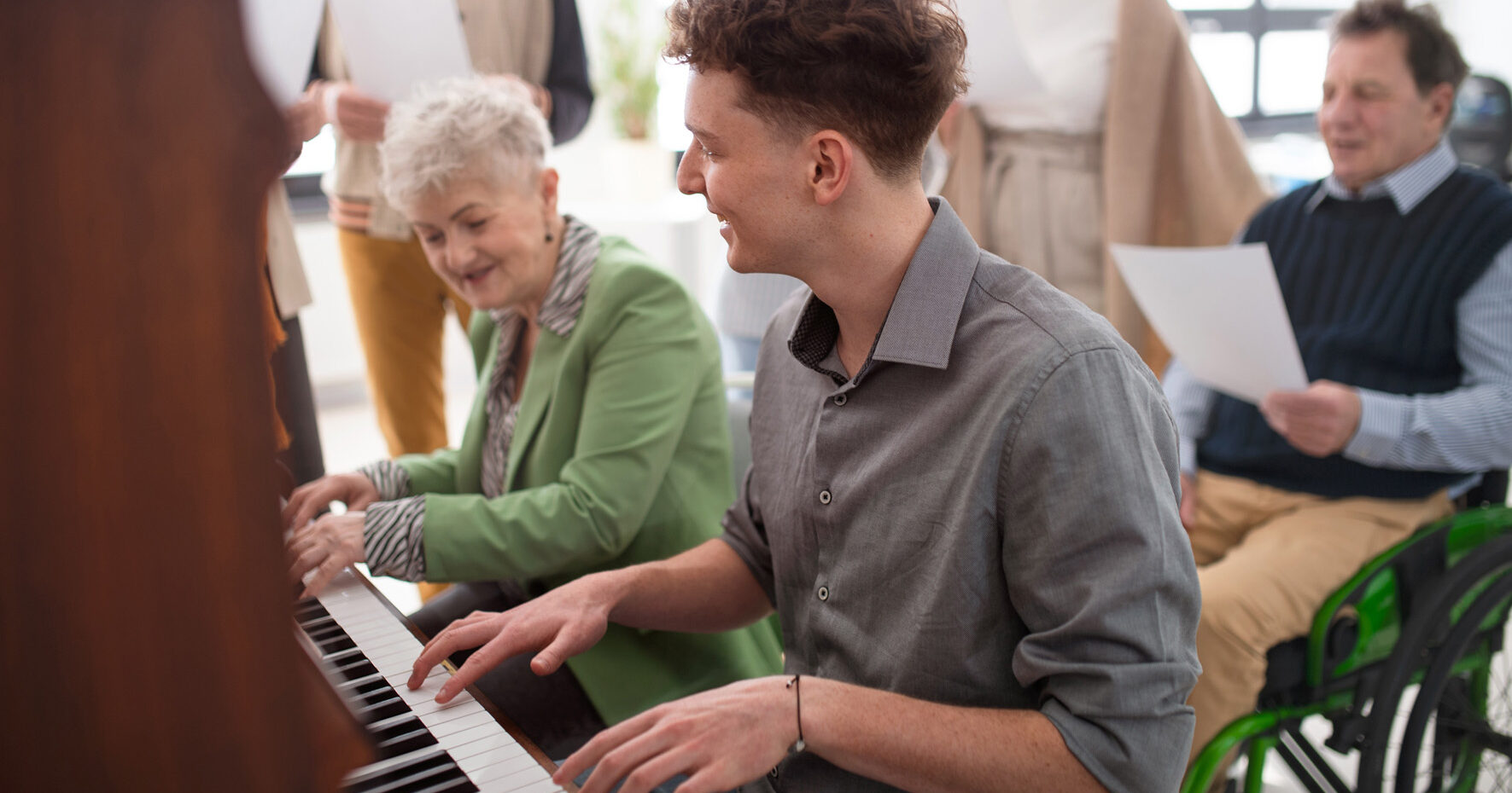senior woman with young teacher playing at piano in choir rehearsal.
