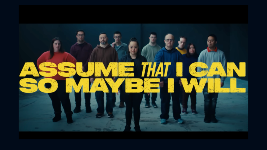 A image of the video - Assume that I can so maybe I will. With people in the background.