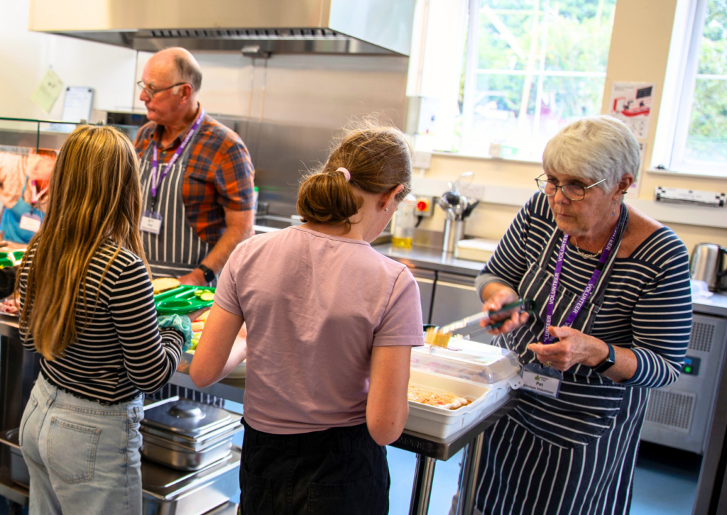 Adult volunteers serve 2 young people food