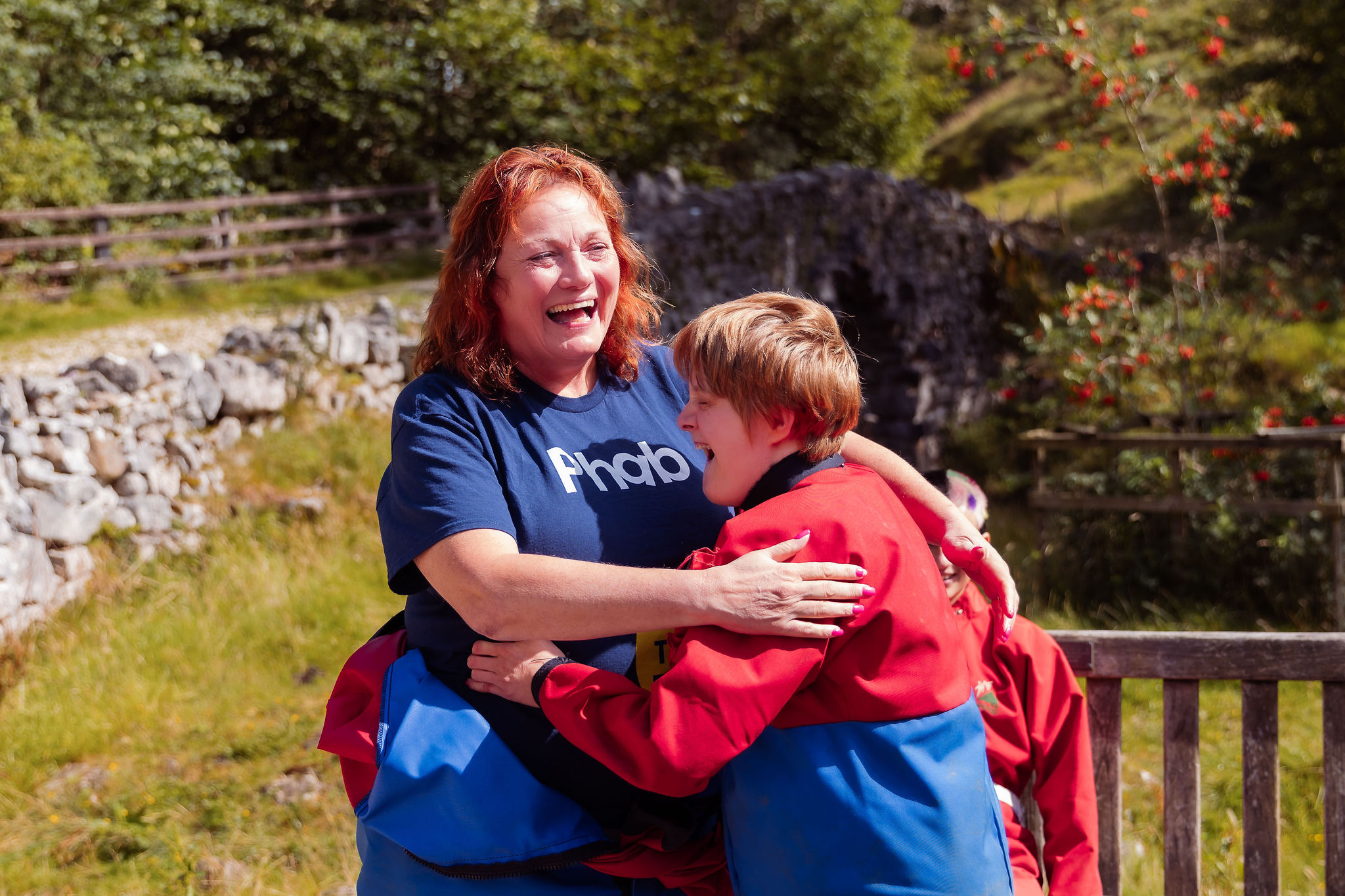 A woman and a child working with Phab hug. They are outside. They are laughing.