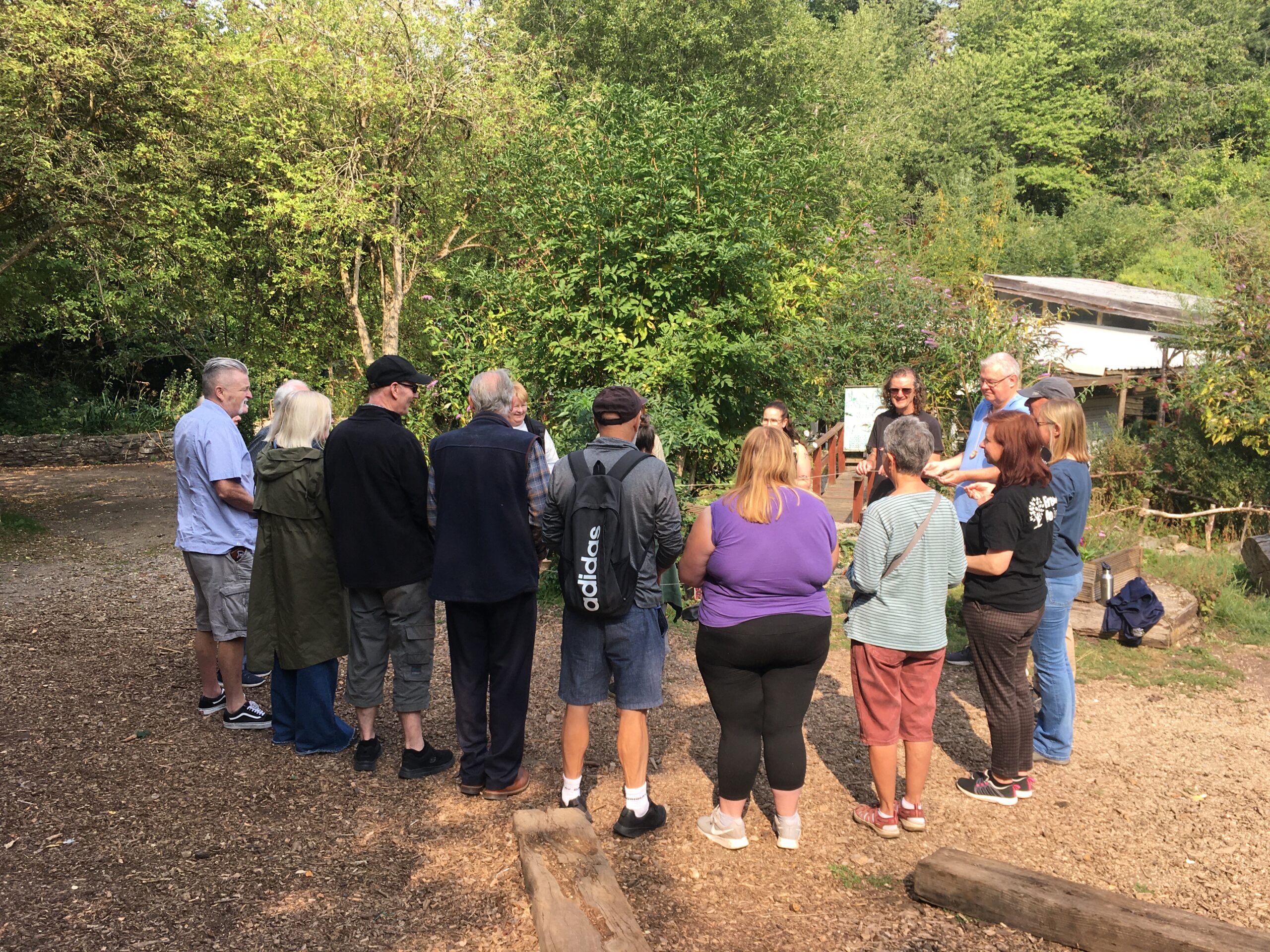 A group of peoples stand in a circle in a forest