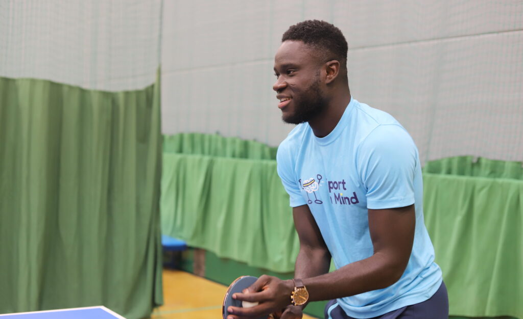 A man in a blue sport in mind shirt plays table tennis