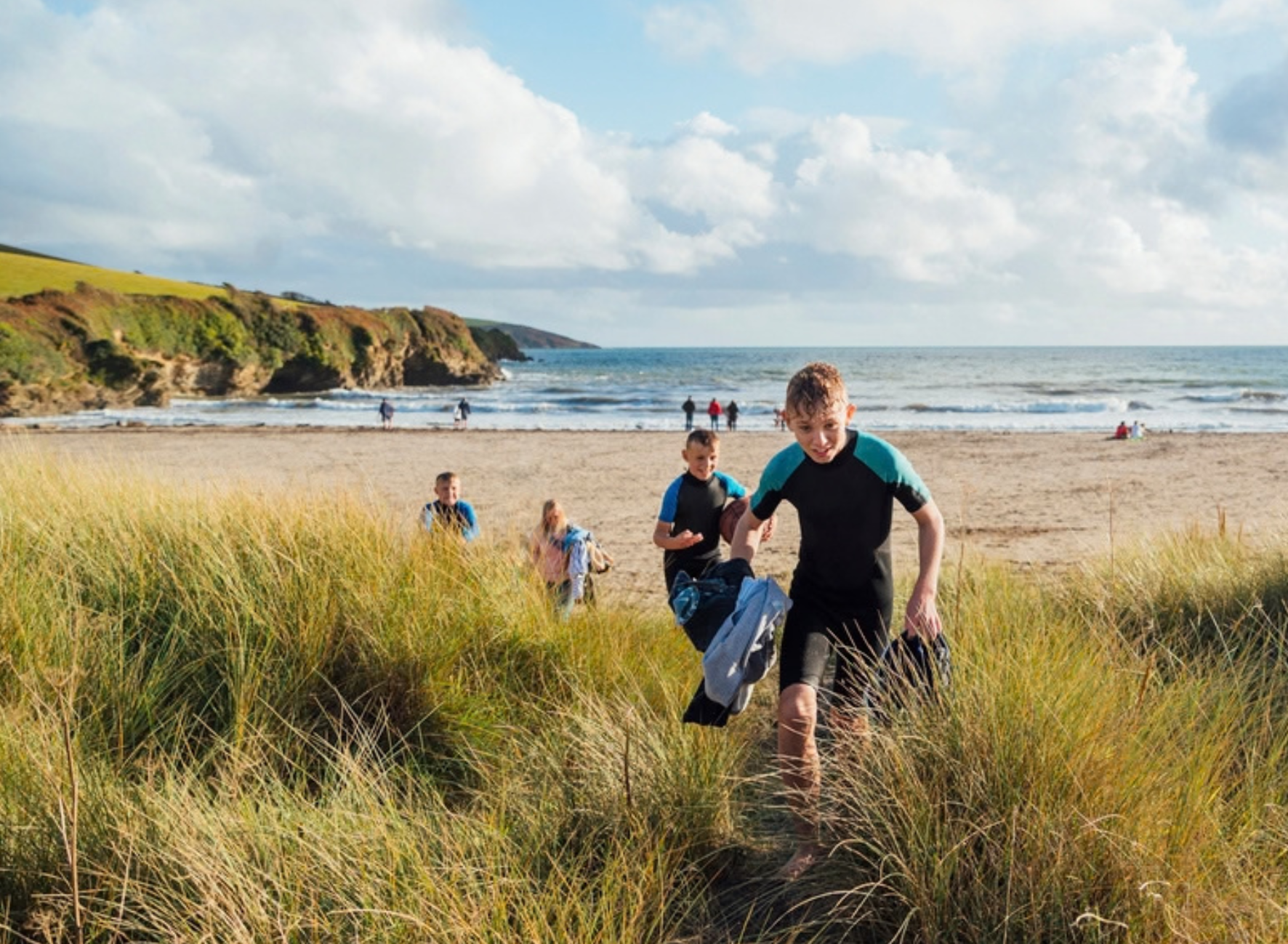 Children run up a sand dune